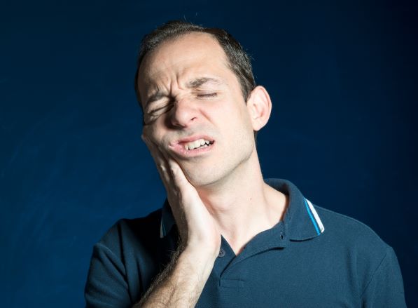 Un hombre se toca la cara debido a un dolor de muelas